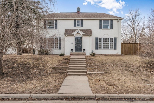 view of front of house featuring a shingled roof, fence, and stucco siding