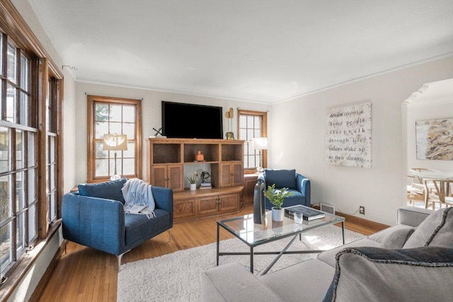 living room featuring baseboards, wood finished floors, visible vents, and ornamental molding