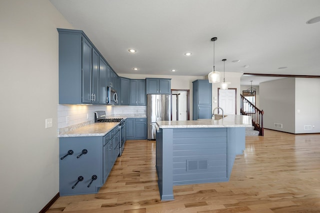 kitchen featuring decorative backsplash, stainless steel appliances, blue cabinets, and light wood-style floors