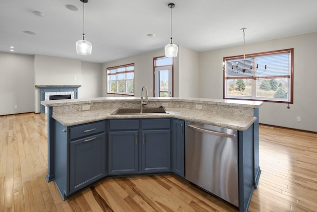 kitchen with dishwasher, blue cabinetry, light wood-style floors, and a sink