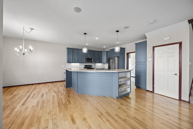 kitchen featuring light wood finished floors, blue cabinetry, decorative backsplash, appliances with stainless steel finishes, and a notable chandelier