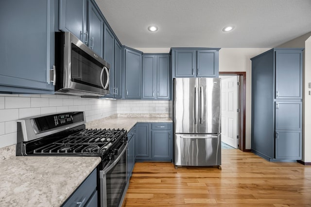 kitchen with blue cabinets, stainless steel appliances, light wood-style flooring, and light countertops