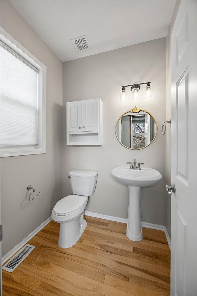 bathroom featuring visible vents, baseboards, toilet, and wood finished floors