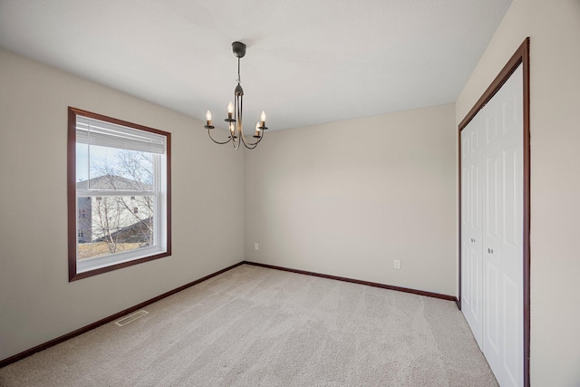 spare room with visible vents, light carpet, a notable chandelier, and baseboards