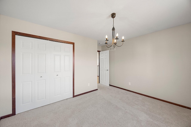 unfurnished bedroom featuring carpet, visible vents, baseboards, a closet, and a chandelier