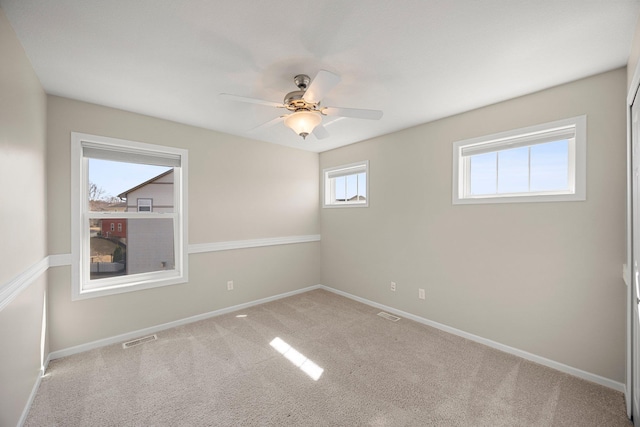 carpeted empty room with visible vents, baseboards, and ceiling fan