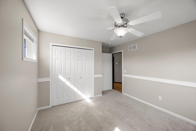 unfurnished bedroom with a closet, visible vents, light colored carpet, and baseboards