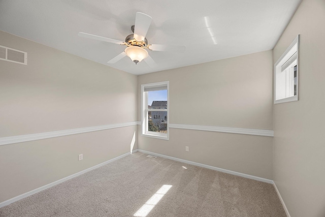 carpeted empty room with visible vents, plenty of natural light, baseboards, and ceiling fan