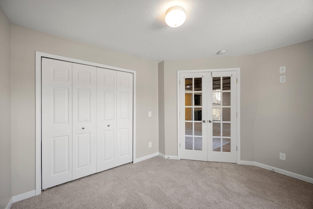 unfurnished bedroom featuring baseboards, carpet flooring, french doors, a closet, and a textured ceiling