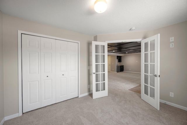 unfurnished bedroom featuring a closet, french doors, baseboards, and carpet