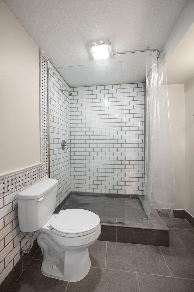 bathroom featuring toilet, a stall shower, and tile patterned flooring