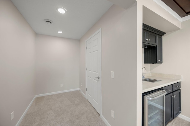 kitchen featuring a sink, wine cooler, light colored carpet, and light countertops