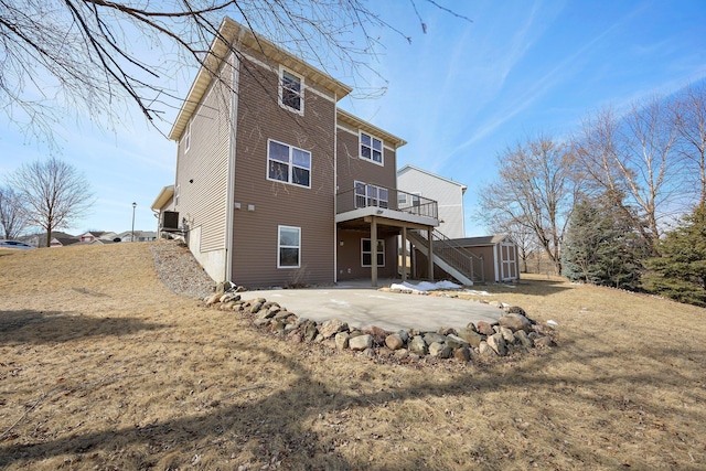 rear view of house featuring an outbuilding, a storage unit, a wooden deck, and a patio