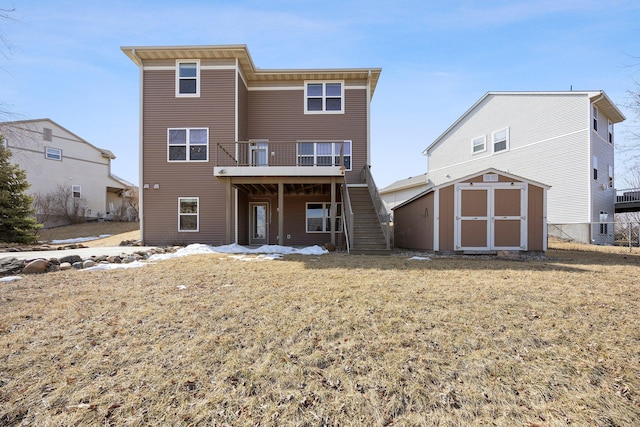 back of property with a storage unit, an outbuilding, a yard, a wooden deck, and stairs