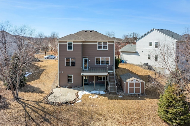 back of property with stairs, an outdoor structure, a deck, a storage shed, and a patio area