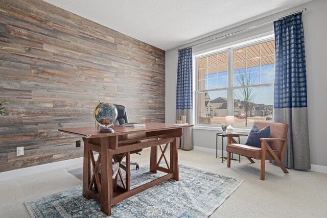 carpeted office space featuring an accent wall, baseboards, wood walls, and a textured ceiling