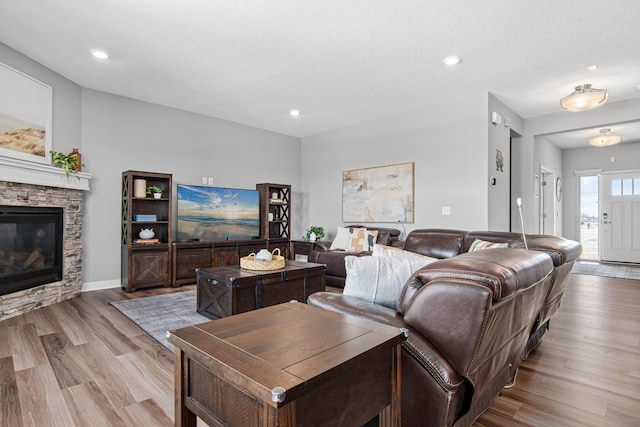 living area featuring recessed lighting, a textured ceiling, wood finished floors, and a fireplace