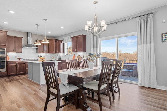 dining space with a wealth of natural light, light wood-style floors, and an inviting chandelier