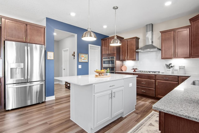 kitchen with decorative light fixtures, decorative backsplash, appliances with stainless steel finishes, light wood-style floors, and wall chimney exhaust hood