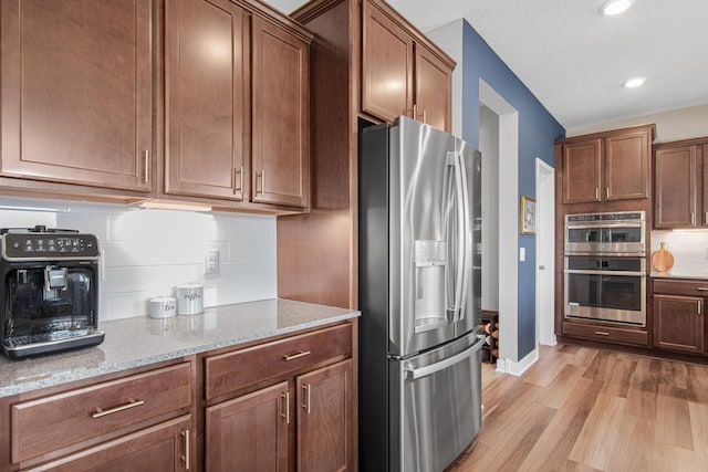 kitchen featuring light stone countertops, baseboards, light wood-style flooring, recessed lighting, and stainless steel appliances