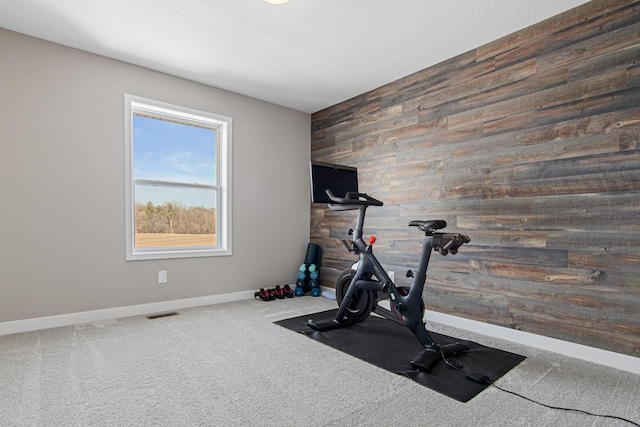 workout room with visible vents, a textured ceiling, carpet, wood walls, and baseboards