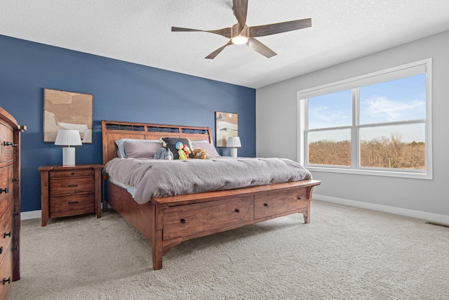 bedroom featuring light colored carpet, baseboards, visible vents, and a textured ceiling