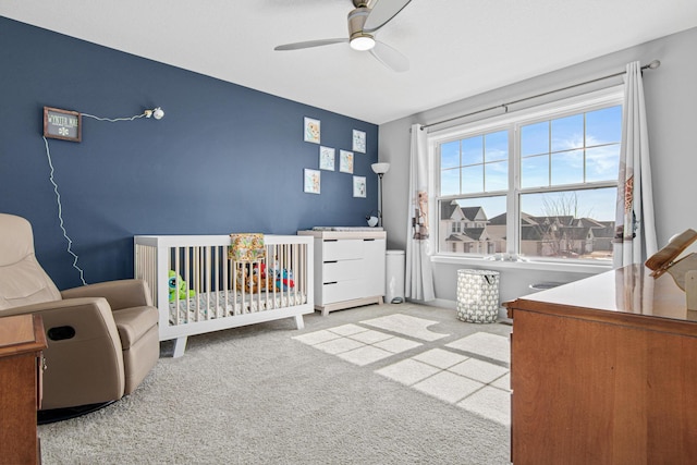 bedroom with a nursery area, carpet, and ceiling fan