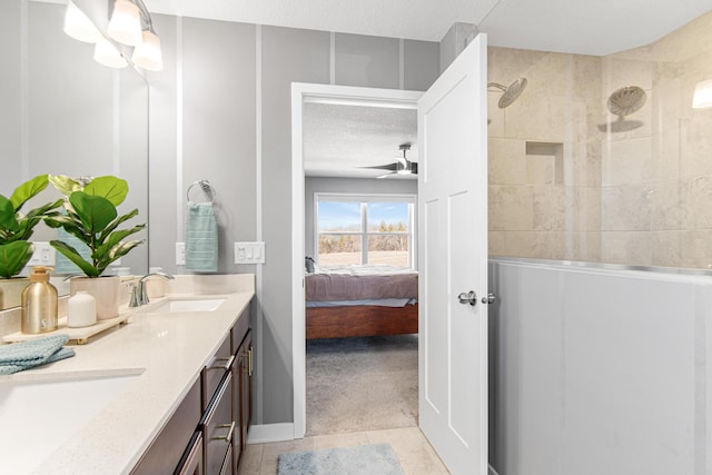 bathroom featuring a ceiling fan, a sink, a tile shower, tile patterned flooring, and double vanity