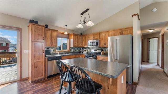 kitchen with dark countertops, backsplash, appliances with stainless steel finishes, and lofted ceiling