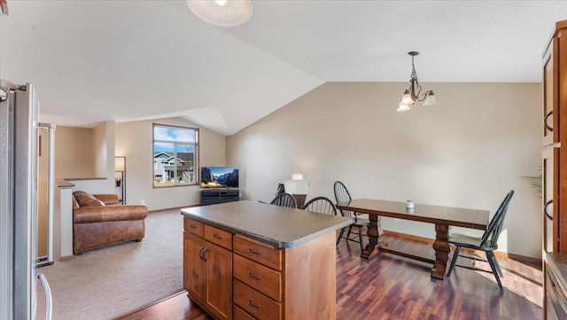 kitchen featuring dark countertops, a kitchen island, open floor plan, lofted ceiling, and freestanding refrigerator