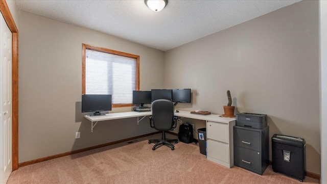 office area featuring baseboards, light carpet, and a textured ceiling