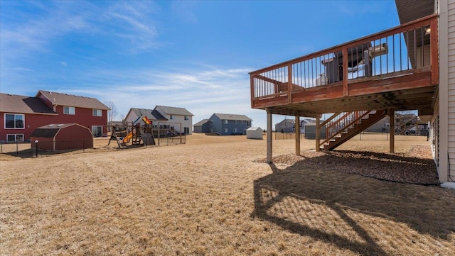 view of yard with a deck, fence, a playground, stairway, and a residential view