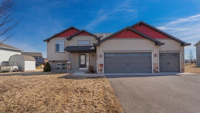 craftsman house featuring aphalt driveway, stone siding, and a garage