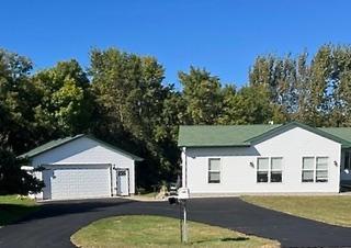 view of front of home featuring a detached garage, an outbuilding, and a front yard