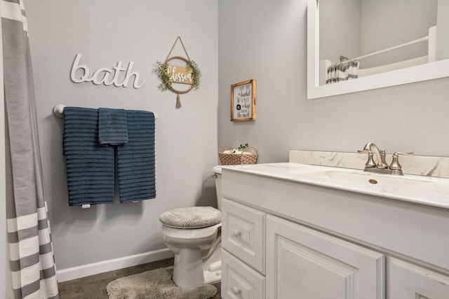 bathroom with vanity, curtained shower, toilet, and baseboards