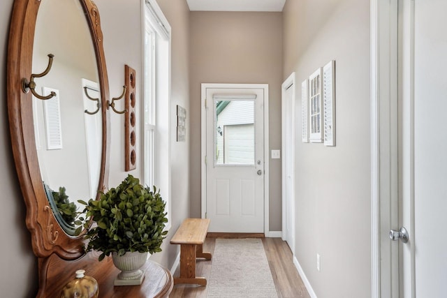 doorway with light wood-style flooring and baseboards