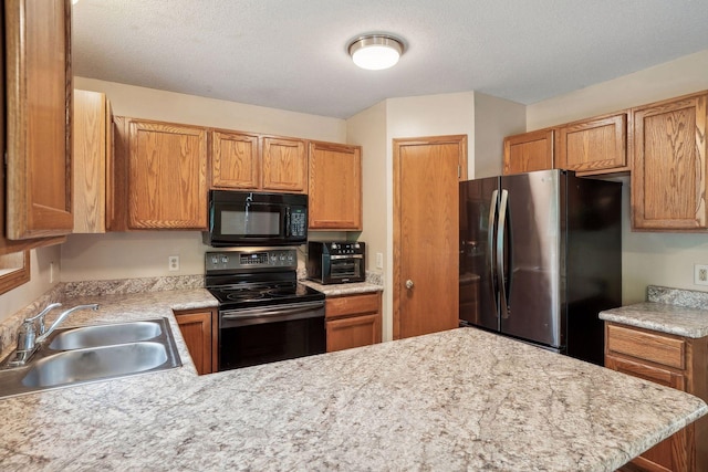 kitchen with black appliances, a sink, a textured ceiling, a peninsula, and light countertops