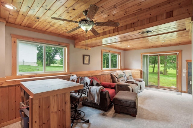 living area featuring a wealth of natural light, visible vents, light colored carpet, and wooden ceiling