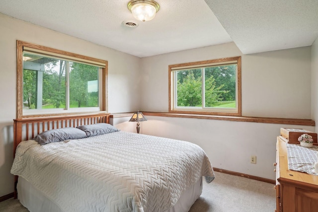 carpeted bedroom with visible vents, a textured ceiling, and baseboards