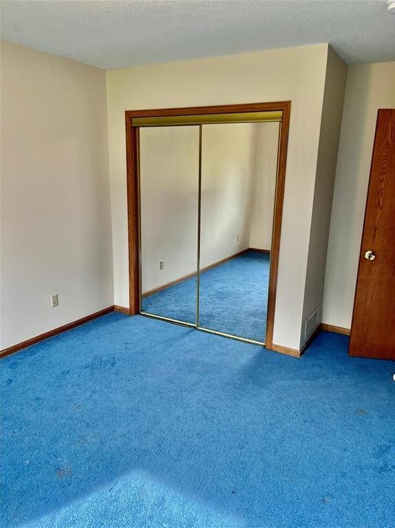 unfurnished bedroom with a closet, baseboards, a textured ceiling, and carpet flooring