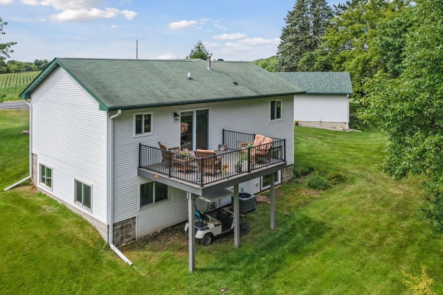 back of property with a deck, a lawn, and a shingled roof