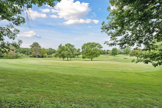 view of property's community featuring view of golf course and a yard