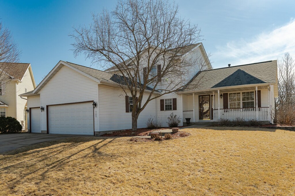 traditional home with a garage, a front lawn, a porch, and driveway