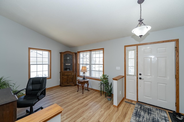 entryway featuring vaulted ceiling, plenty of natural light, baseboards, and light wood finished floors