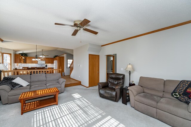 living room with a textured ceiling, crown molding, light colored carpet, ceiling fan, and vaulted ceiling