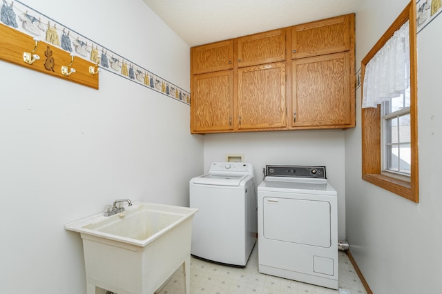 laundry area featuring a sink, cabinet space, light floors, and washer and dryer