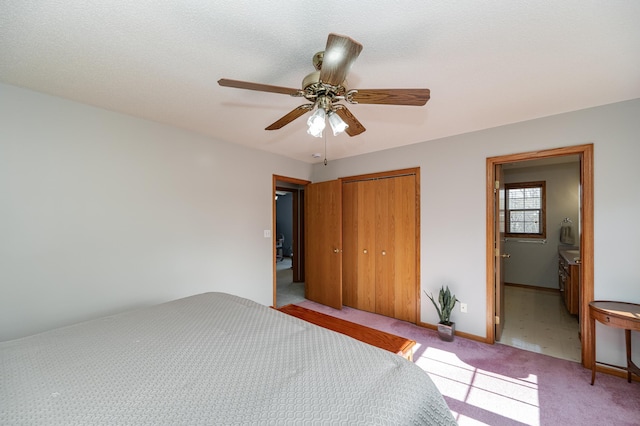 unfurnished bedroom featuring light carpet, ensuite bathroom, a ceiling fan, a closet, and baseboards