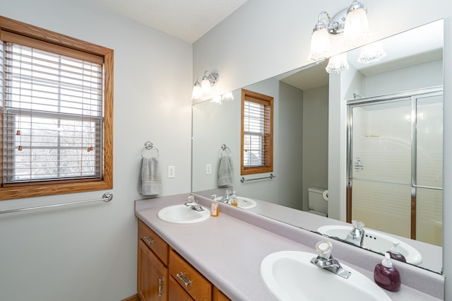 bathroom with toilet, a stall shower, and a sink