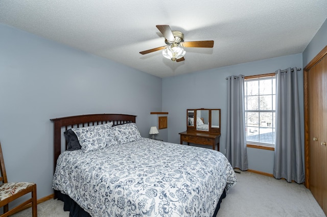 bedroom with a textured ceiling, baseboards, a closet, and light carpet