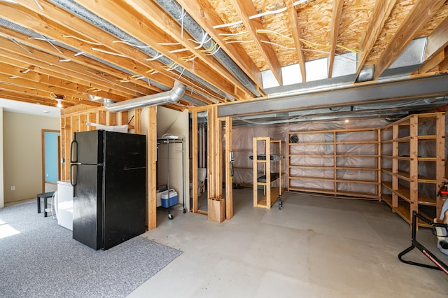 unfinished basement featuring freestanding refrigerator